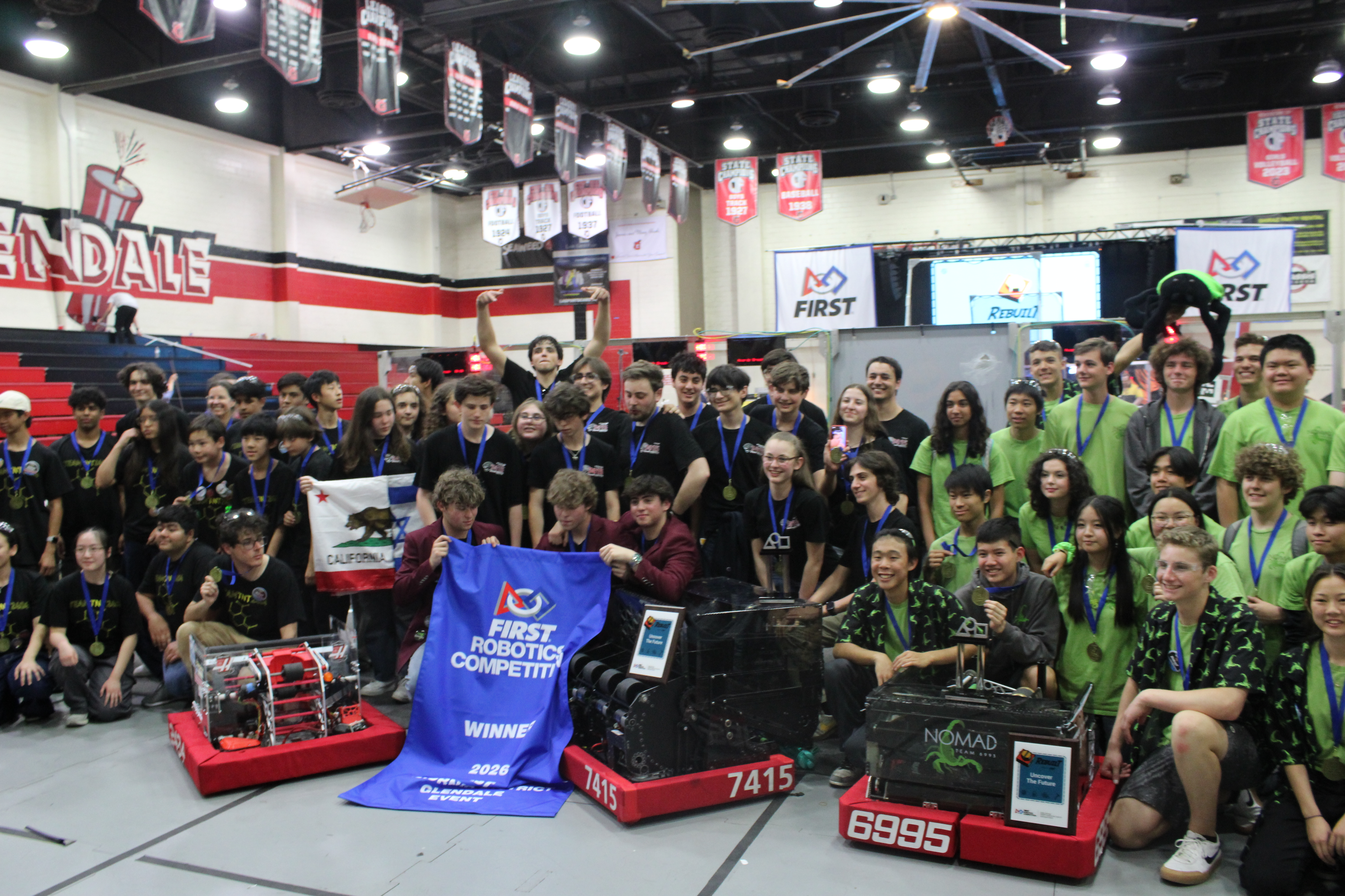 Team 7415 celebrating with their winning alliance and the blue banner